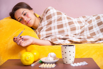 girl lying in bed and measures the temperature