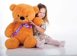 Child girl embraces teddy bear, studio