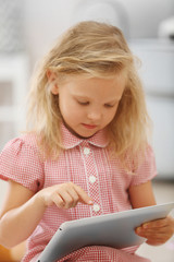Little girl with tablet in the room