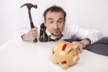 Businessman is trying to break the piggybank with hammer