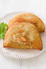 pie with meat with basil on white plate on white wooden background