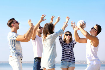 Young people playing with ball on the riverside