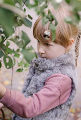 autumn portrait of a little blond girl in fur waistcoat  in a park