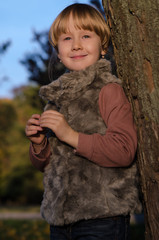 autumn portrait of a little blond girl in fur vest in a park