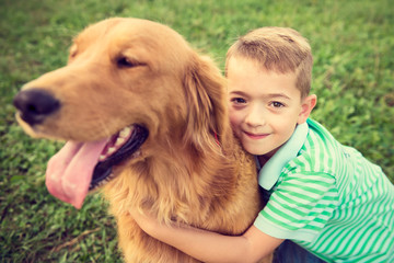 Obrazy na Szkle  Śliczny mały chłopiec przytulający swojego psa golden retrievera