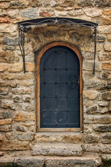 Arched medieval wooden door in a stone wall.
