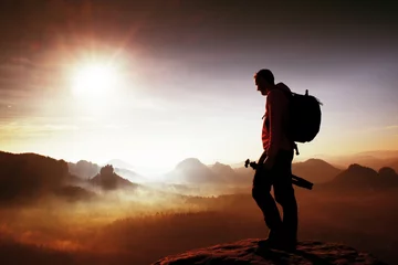 Zelfklevend Fotobehang Silhouet van fotograaf met uitzicht op een deken van mist over de vallei naar de zon © rdonar