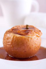 Baked apple with cottage cheese, caramel and cinnamon on white ceramic plate on white background.