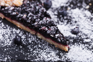 Galette with blueberries  on a black background.