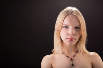 Portrait of a young beautiful lady with necklace isolated over black background