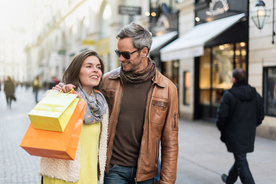Stylish couple walking in a cobbled car-free street, shopped 