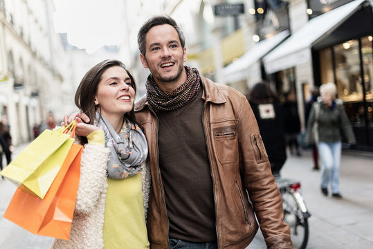 Stylish couple walking in a cobbled car-free street, shopped 