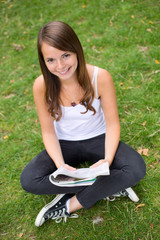 young woman holding a magazine in the park