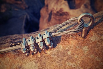Solid knot on steel rope. Iron twisted rope fixed in block by screws snap hooks. Detail of rope end...