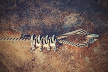 Solid knot on steel rope. Iron twisted rope fixed in block by screws snap hooks. Detail of rope end...