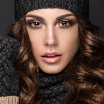Beautiful girl with Smokeymakeup, curls in black knit hat. Warm