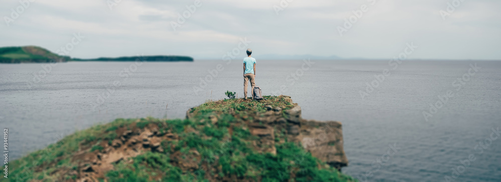 Poster hiker girl standing on peak of mountain and enjoying view of sea