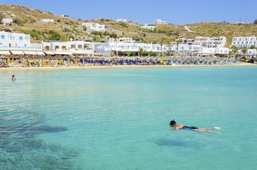 Platis Gialos beach on greek island Mykonos, Greece. A view of the crystal clear blue sea, sunbeds,...