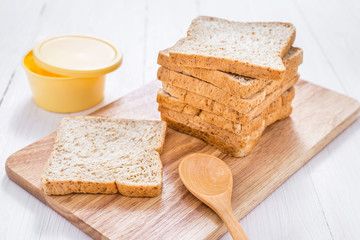 Sliced whole wheat bread with butter on white wooden table