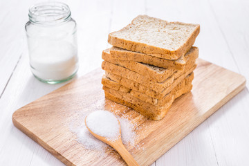 Sliced whole wheat bread with sugar on white wooden table