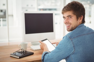 Fototapeta na wymiar Happy businessman using digital tablet while sitting at desk 