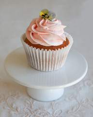 Homemade pink frosting vanilla cupcakes with edible flowers