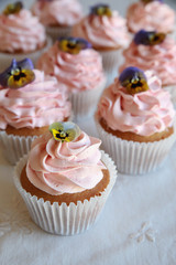 Homemade pink frosting vanilla cupcakes with edible flowers