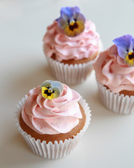 Homemade pink frosting vanilla cupcakes with edible flowers