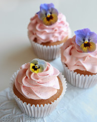 Homemade pink frosting vanilla cupcakes with edible flowers