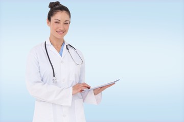 Composite image of happy doctor using her tablet pc
