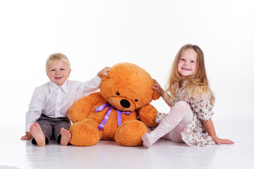 Boy and girl are sitting with big teddy bear