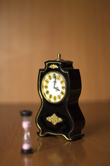 hourglass standing next to the old clock on the table