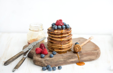 Buckwheat pancakes with fresh berries and honey on rustic wooden