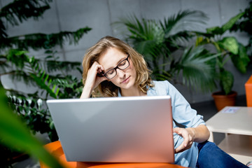 Beautiful young businesswoman using mobile phone while working w