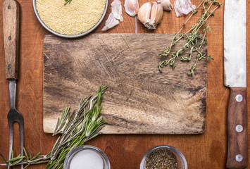 Couscous herb knife meat fork garlic and salt seasoning cutting board. Ingredients on wooden rustic background close up top view