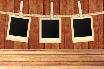 old photo cards hanging on rope on clothespins over wooden backg