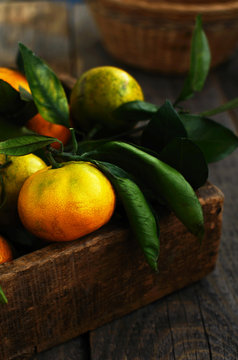 Wooden crate with fresh green, yellow and orange tangerines