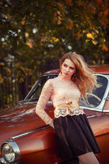 stylish woman standing with a retro car in fashion dress