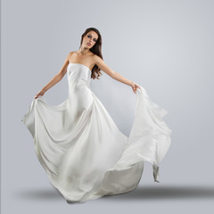 Fototapeta na wymiar beautiful young girl in flying white dress. Flowing fabric