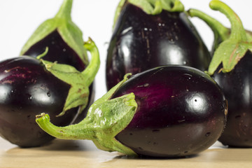 Purple eggplants on wooden table and white background