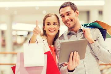 couple with tablet pc and shopping bags in mall