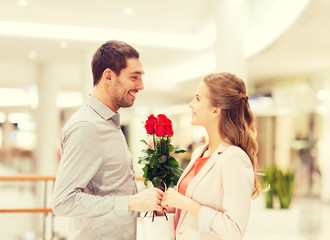 happy young couple with flowers in mall