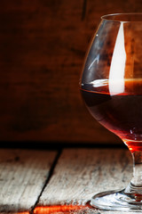 Cognac in a glass on the old wooden background, selective focus