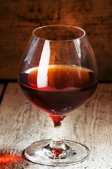 Cognac in a glass on the old wooden background, selective focus