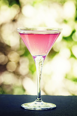 Cosmopolitan cocktail on a summer green nature bokeh background,