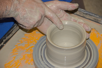 Potter makes on the pottery wheel clay jug. The hands of a potte