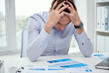 stressed businessman with papers in office