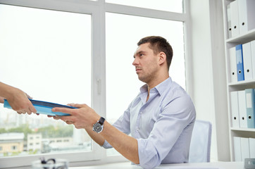 businessman taking papers from secretary in office