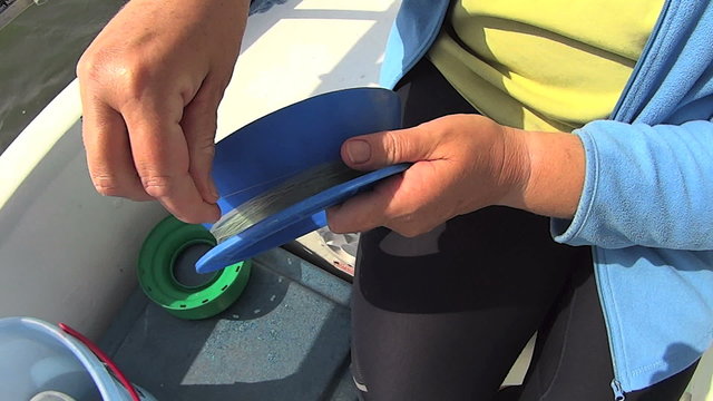 Fishing hand line being wound on to a plastic fishing reel. 