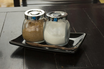 Brown sugar and cream in the glass bottles on the table